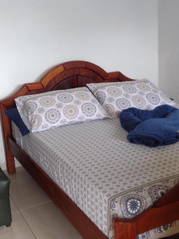a wooden bed with blue pillows on it at Beautiful day suítes in Ilhabela