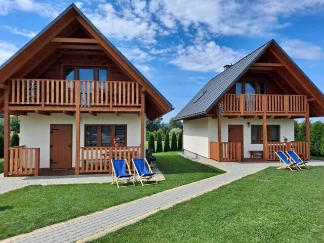 a house with two blue chairs in front of it at Domki w Bieszczadach - Apartamenty in Hoczew