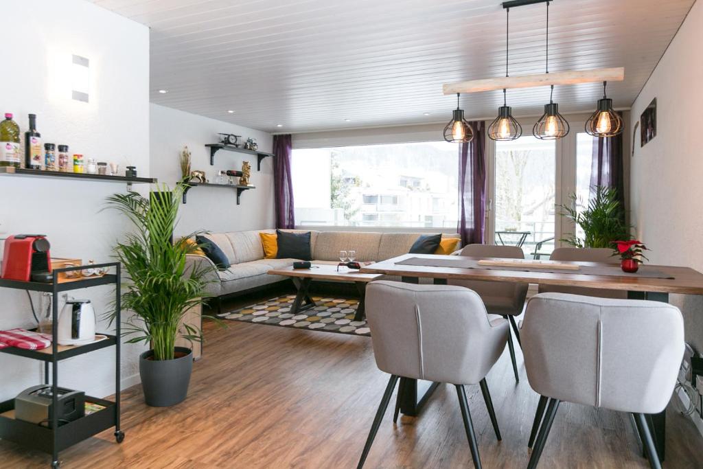 ein Wohnzimmer mit einem Tisch, Stühlen und einem Sofa in der Unterkunft Spirit Apartments - Balkon - Bergsicht - Parkplatz in Engelberg
