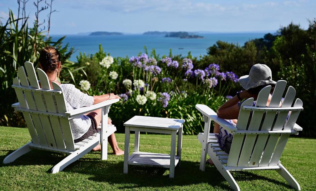 two people sitting in lawn chairs on the grass at Kākā Ridge Retreat Luxury Cottage in Tawharanui