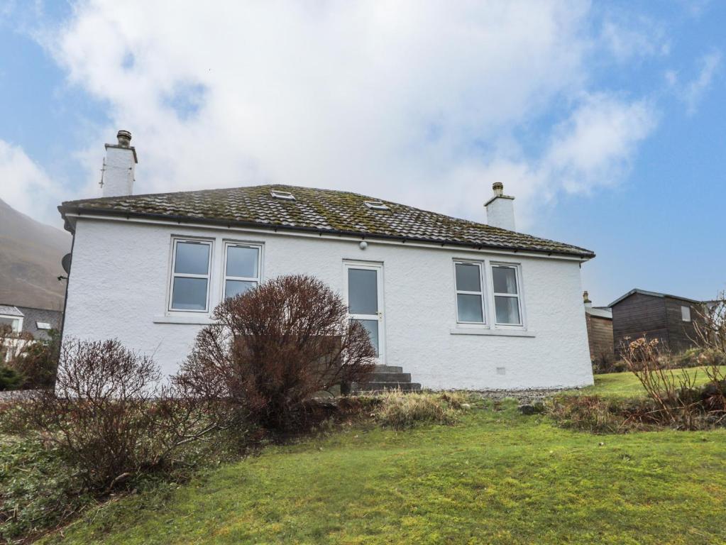 a white house with windows on a grass field at 13 Sconser in Sconser