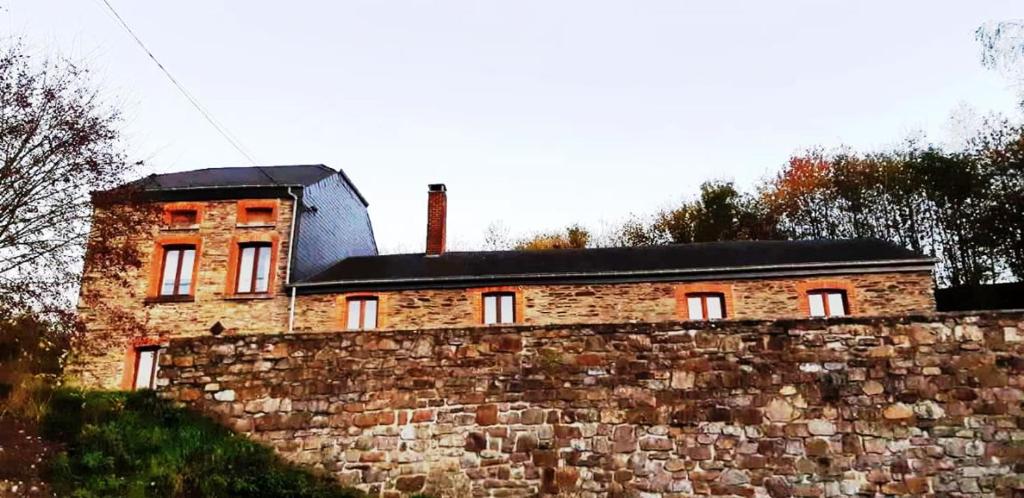um edifício de tijolos no topo de uma parede de pedra em Maison-indi em Houffalize