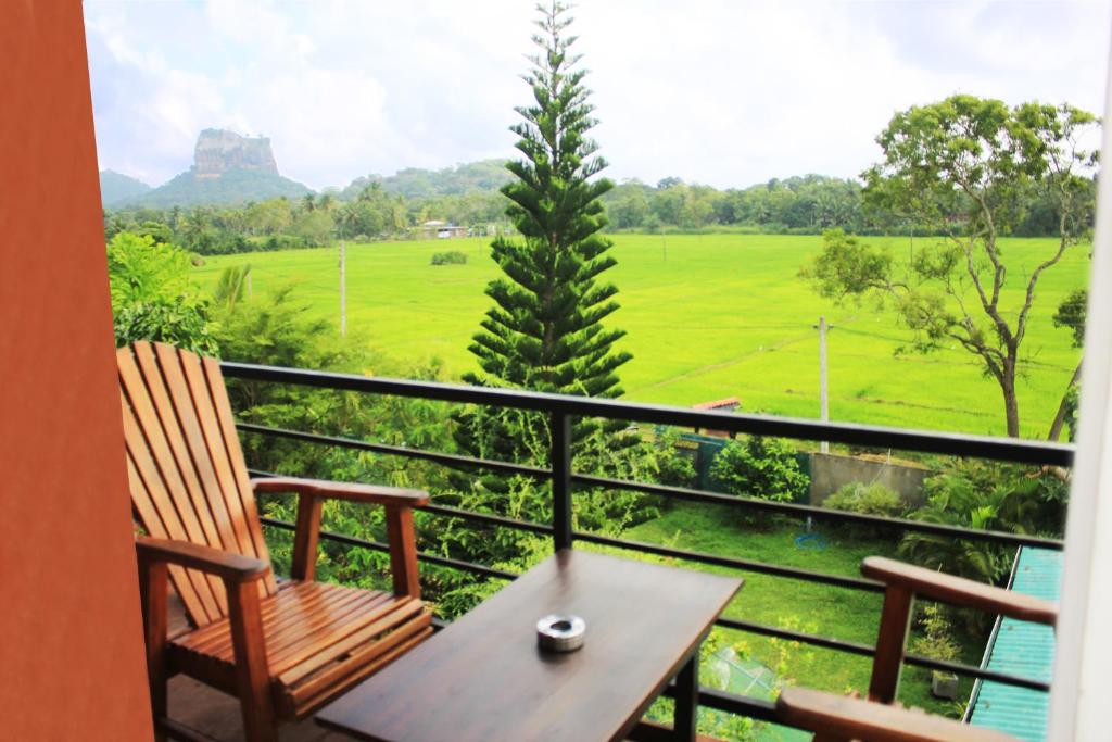 balcón con mesa, sillas y vistas a un campo en Sigiriya Water Guest & View Point Restaurant en Sigiriya
