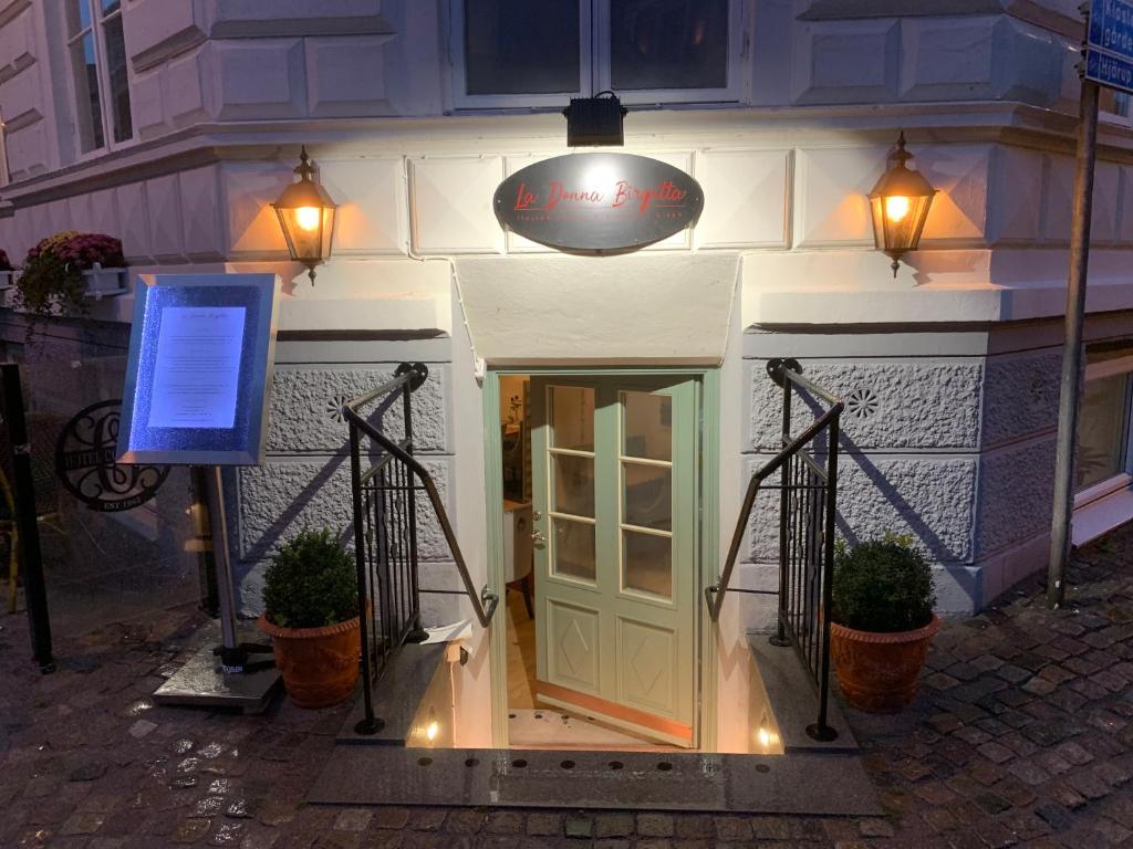 Wejście do przytulnej restauracji schodami w dół, oświetlone lampami i tablicą menu