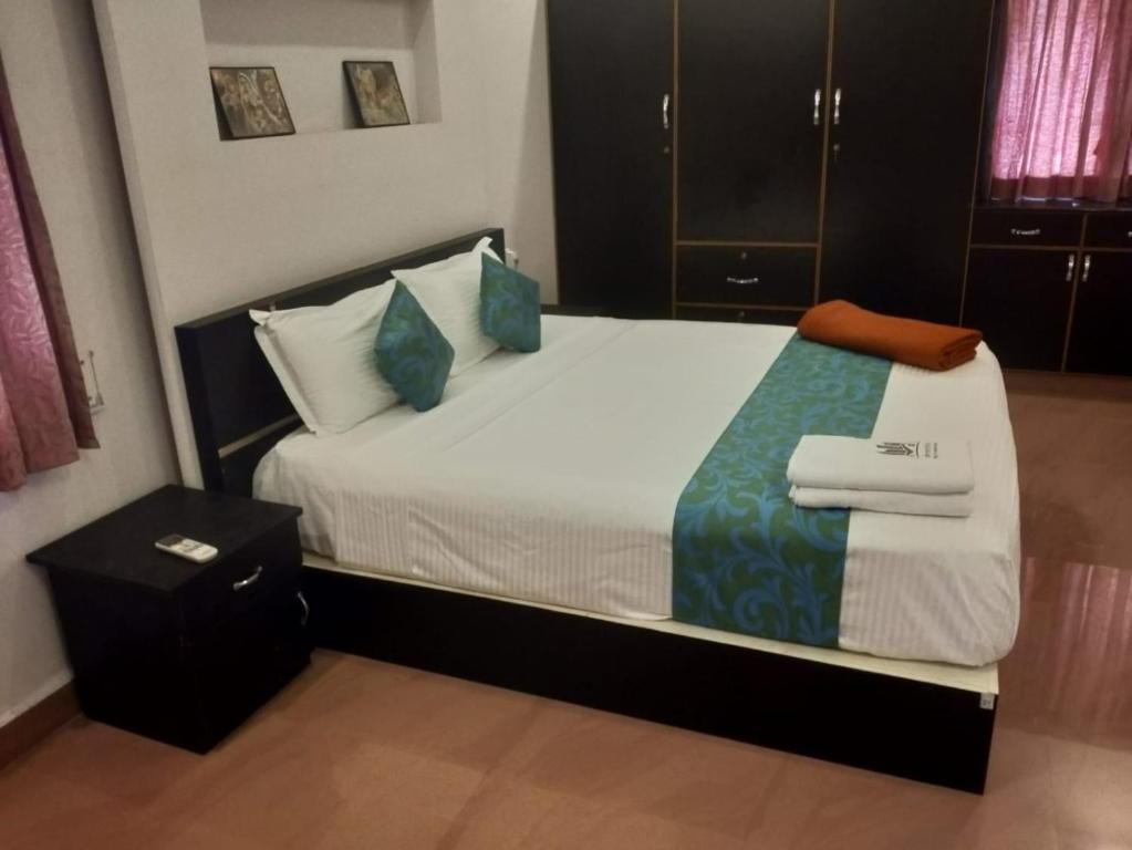 a bedroom with a large bed with blue pillows at Sremethila Homestay in Marudhamalai