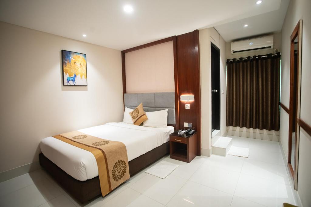 a hotel room with a bed and a window at Jatra Hotel Grand Royal in Dhaka