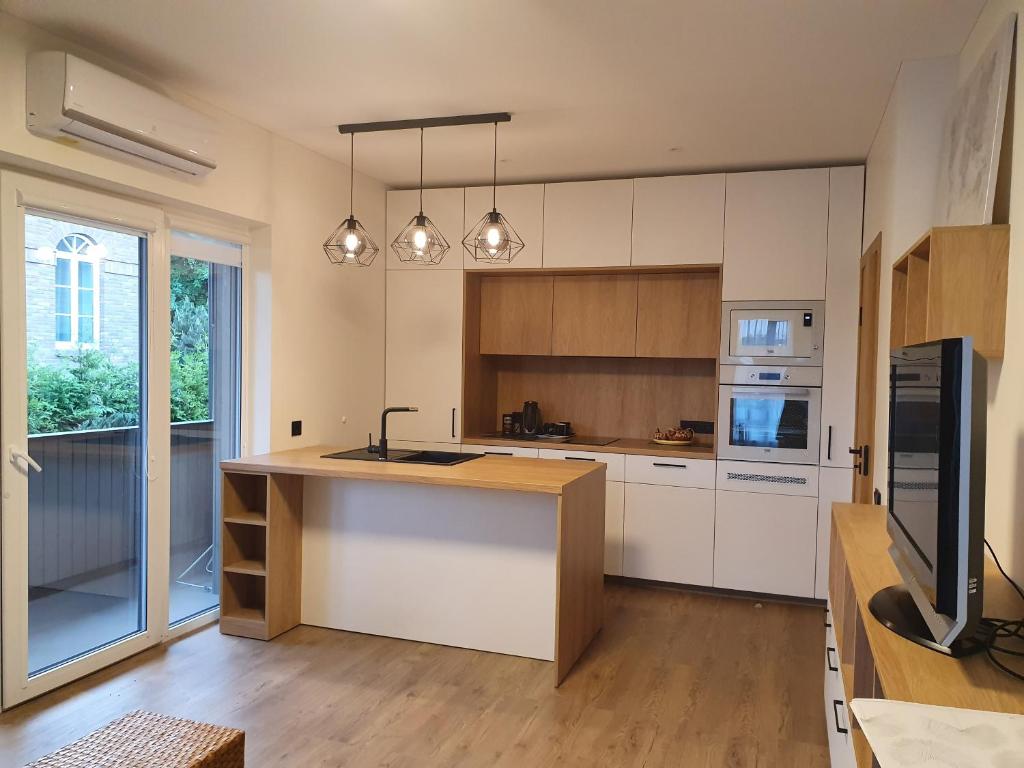 una cocina con armarios blancos y una isla con fregadero en Žvėrynas Workation apartments, en Vilna