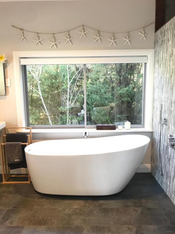 uma banheira na casa de banho com uma grande janela em Wairimu View Lodge em Waipu