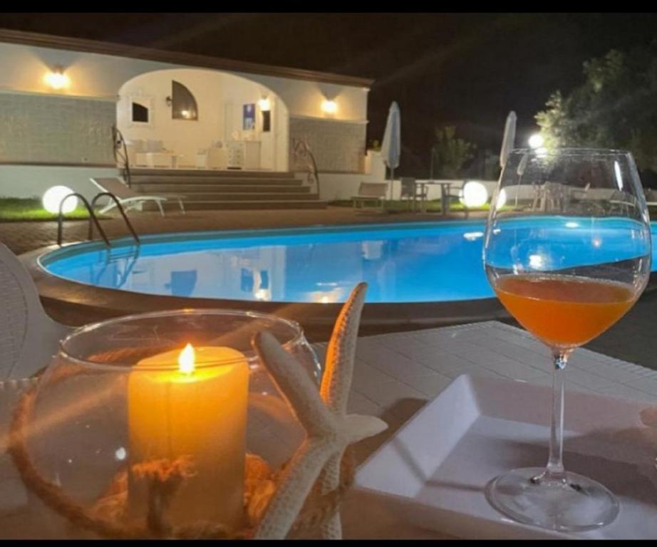 トラッペートにあるVilla Nunziatella Badiaのプールサイドのテーブルの上にワインとキャンドルを用意しています。