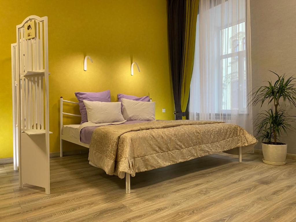 sypialnia z łóżkiem i żółtą ścianą w obiekcie In the heart of Odessa w Odessie