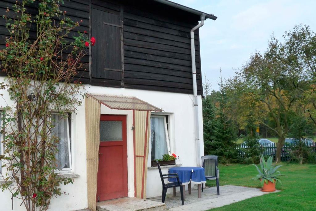 una casa con puerta roja, mesa y sillas en Ferienwohnung Tor zur Ostsee - a55965 en Mellenthin