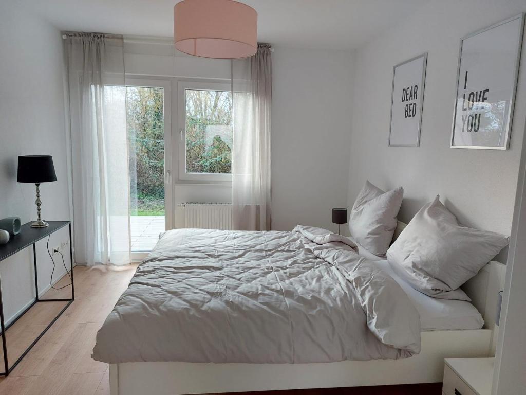 a white bedroom with a bed and a window at Landpartie in Freckenfeld