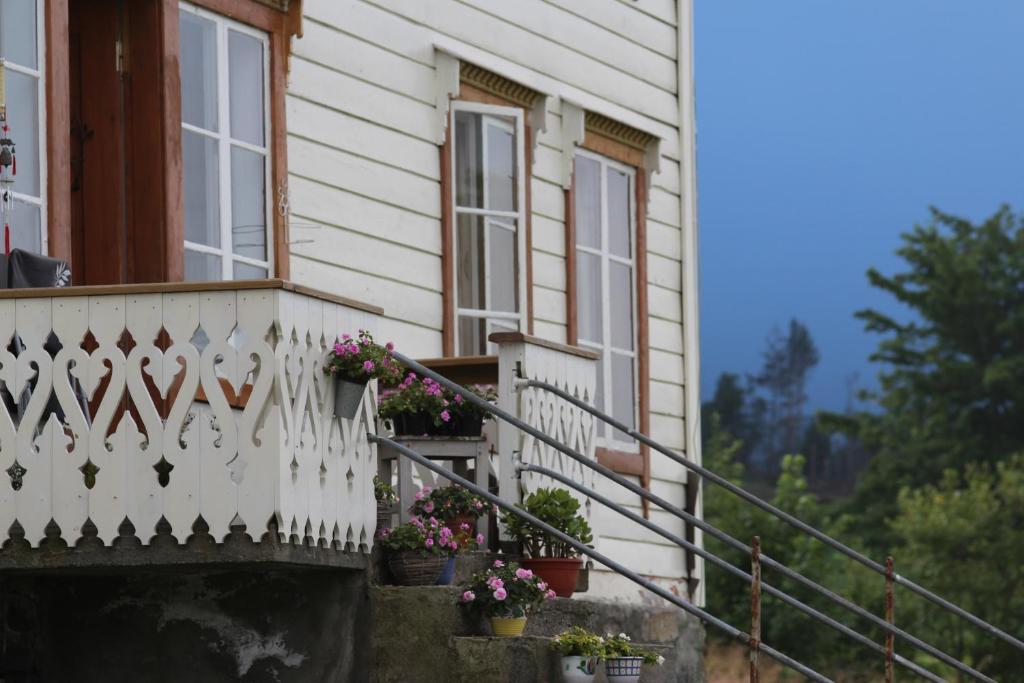 een huis met een wit hek en bloemen op het balkon bij Overvoll Farm in Stranda