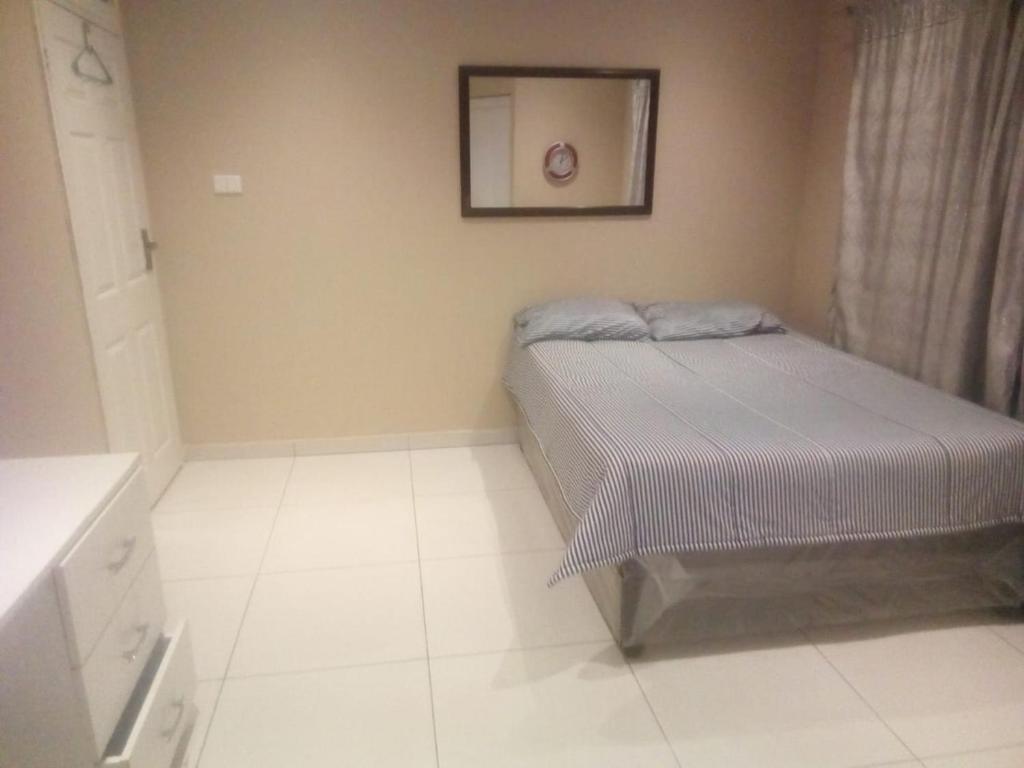a small bedroom with a bed and a picture on the wall at Buttercream in Durban