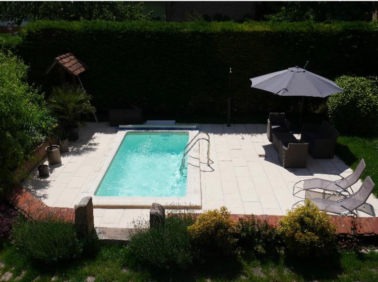 uma piscina com um guarda-sol e duas cadeiras e uma mesa e um guarda-sol em Gîte de Juliana 4 personnes em Sundhouse