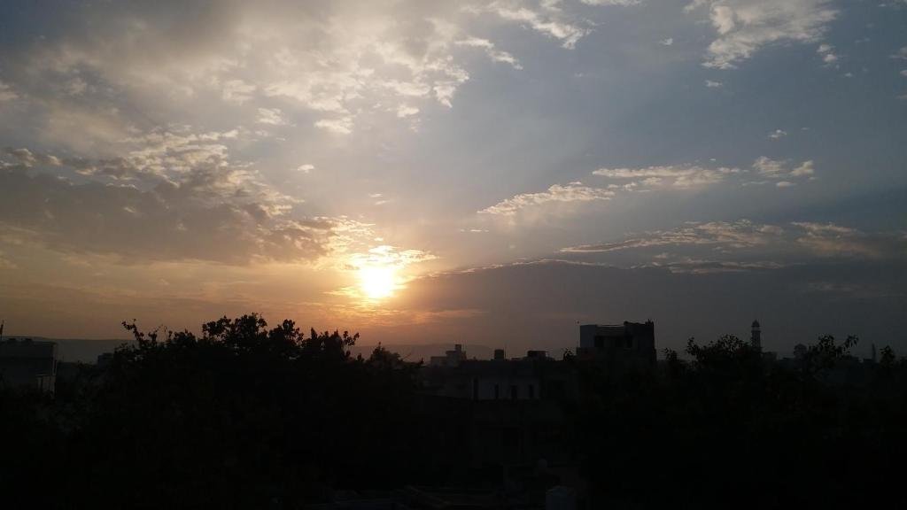 um pôr-do-sol sobre uma cidade com o sol no céu em Swaraj Palace em Jaipur