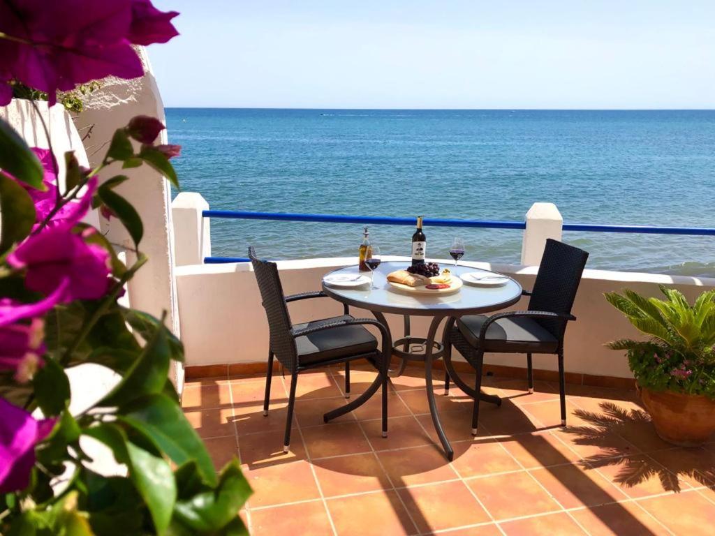 - stół i krzesła na balkonie z widokiem na ocean w obiekcie Beach Side Apartments Calahonda w mieście Sitio de Calahonda