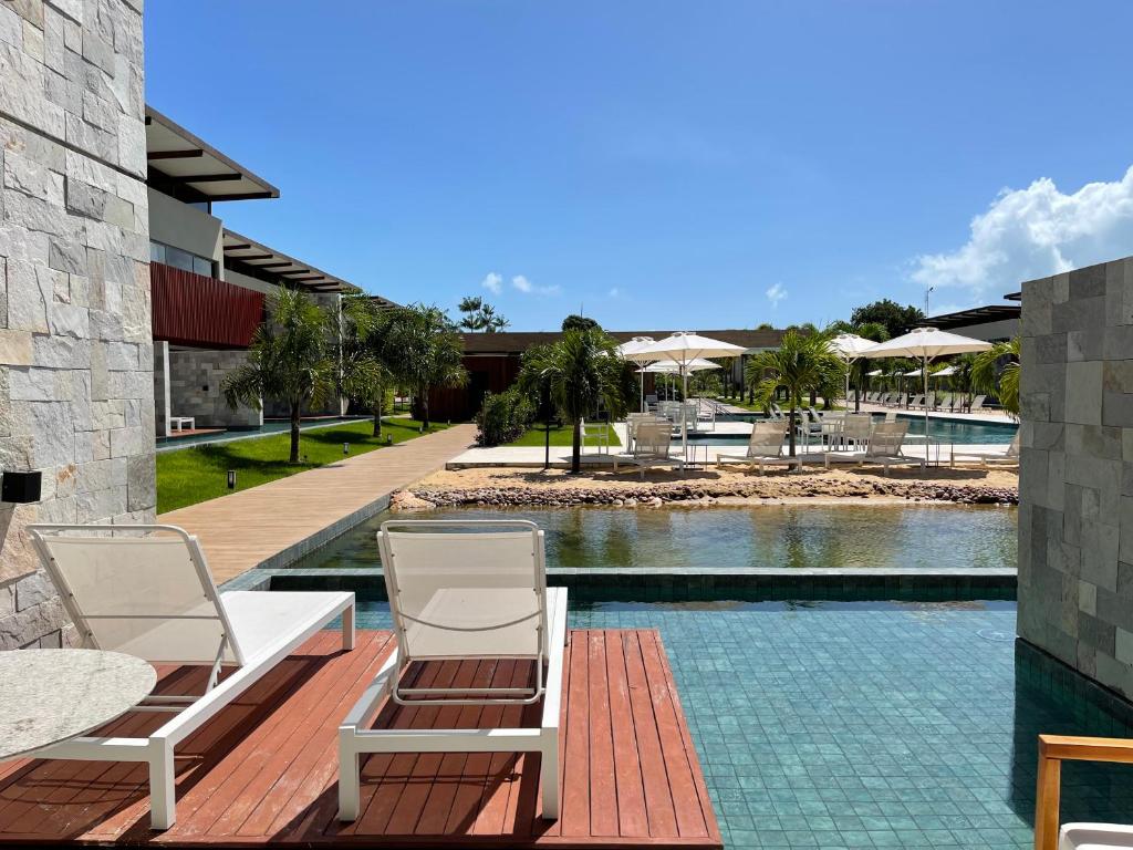 two chairs sitting on a deck next to a swimming pool at Flat Deluxe no centro de Pipa in Pipa