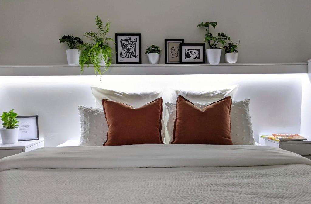 um quarto com uma cama branca com almofadas e plantas em The Botanical 304 em Albury