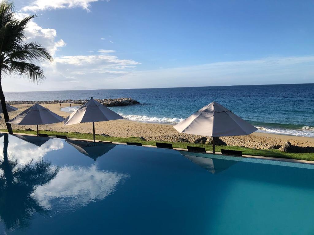 una piscina junto a una playa con sombrillas en Vacations in the Caribbean Paradise, en Sosúa