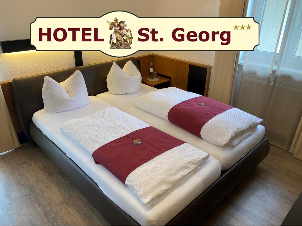 Una cama con dos toallas en ella con un hotel st georg en Hotel garni St.Georg, en Sankt Wolfgang