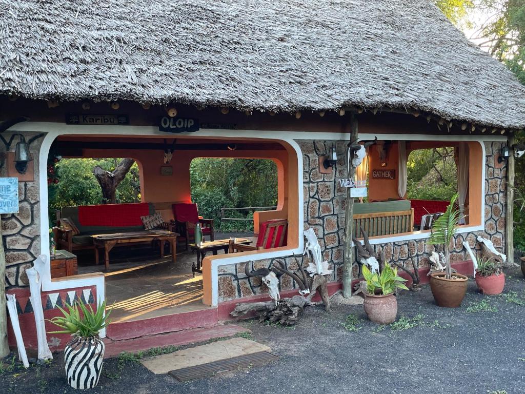 a small house with a thatch roof and a porch at Maasai Simba Camp in Amboseli