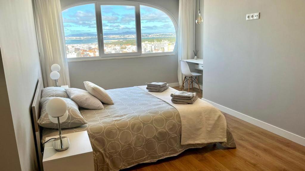 um quarto com uma cama e uma janela grande em T2 com uma vista deslumbrante sobre o Atlântico! em Costa da Caparica