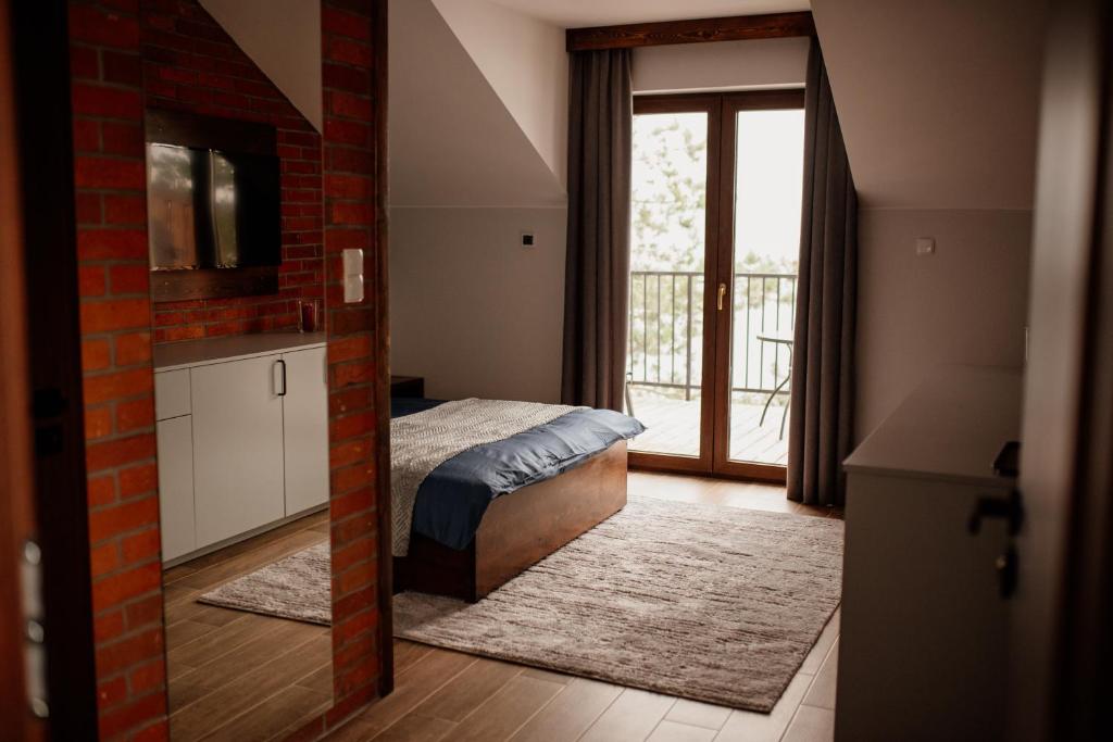 1 dormitorio con 1 cama y puerta a un balcón en Azyl Widoki en Wielkie Leżno