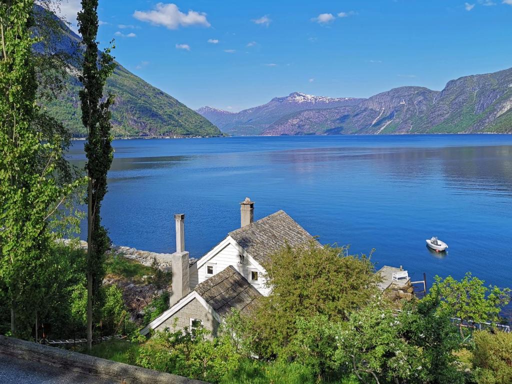 a house on the shore of a lake with a boat at Fjordperlen in Eidfjord