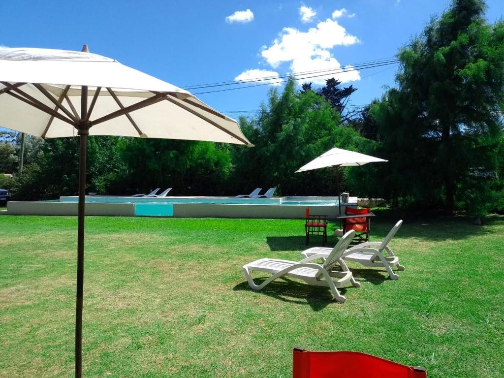 two chairs and a table and two umbrellas in a yard at Casa Magnolias in Tandil