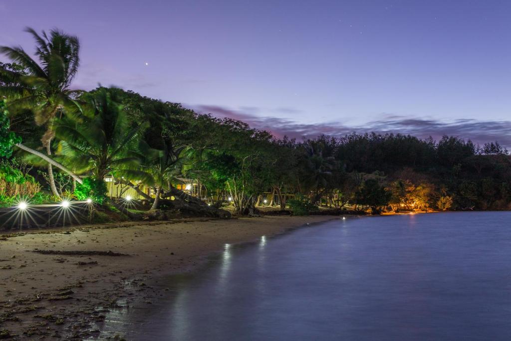 a beach with palm trees and the ocean at night at Funky Fish Beach & Surf Resort in Malolo
