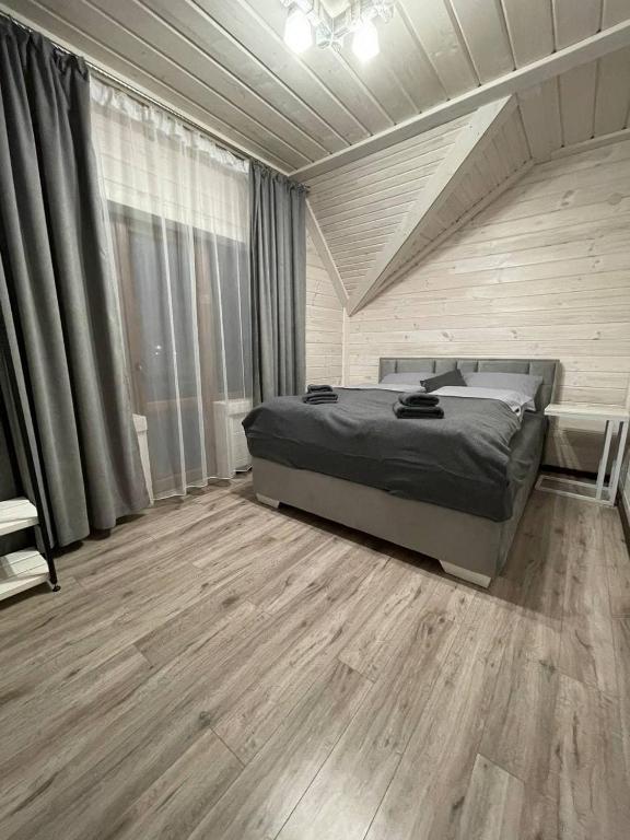een slaapkamer met een bed en een houten vloer bij Happy House in Slavske