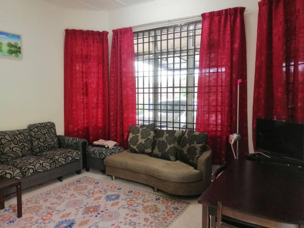 a living room with a couch and red curtains at AziziYati Muslem Homestay KLIA Sepang - SemiD House in Sepang