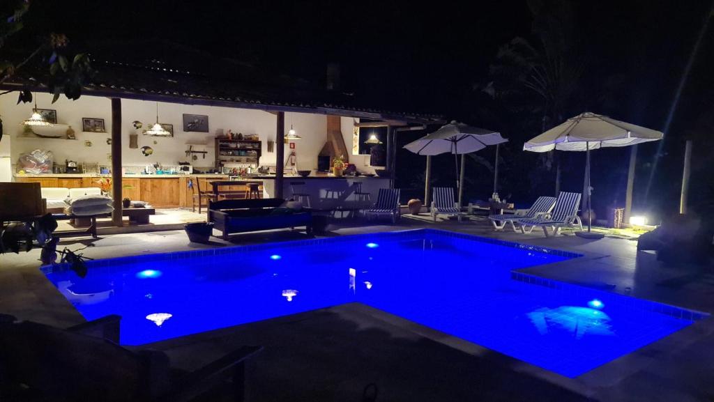 a swimming pool with blue lighting in a backyard at night at Pousada Pandoro in Trancoso