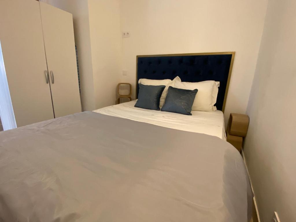 a white bed with two blue pillows on it at Au 5eme ciel in Draguignan