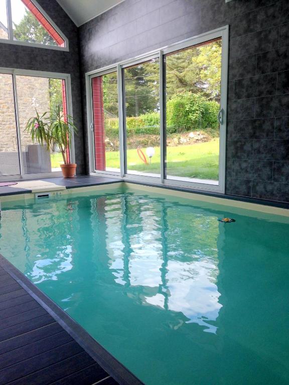 a large swimming pool with blue water in a house at gîte Brocéliande - Harmonie et tranquillité près de la mer in Theix