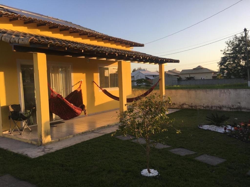 a house with a porch with a hammock on it at Aconchegante Casa de Temporada Araruama in Araruama