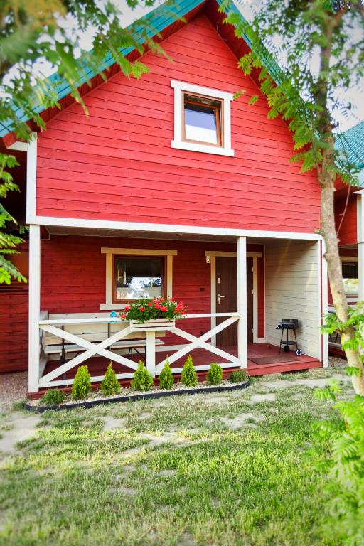 a red house with a porch and a window at Domki Leśny Zakątek in Pogorzelica