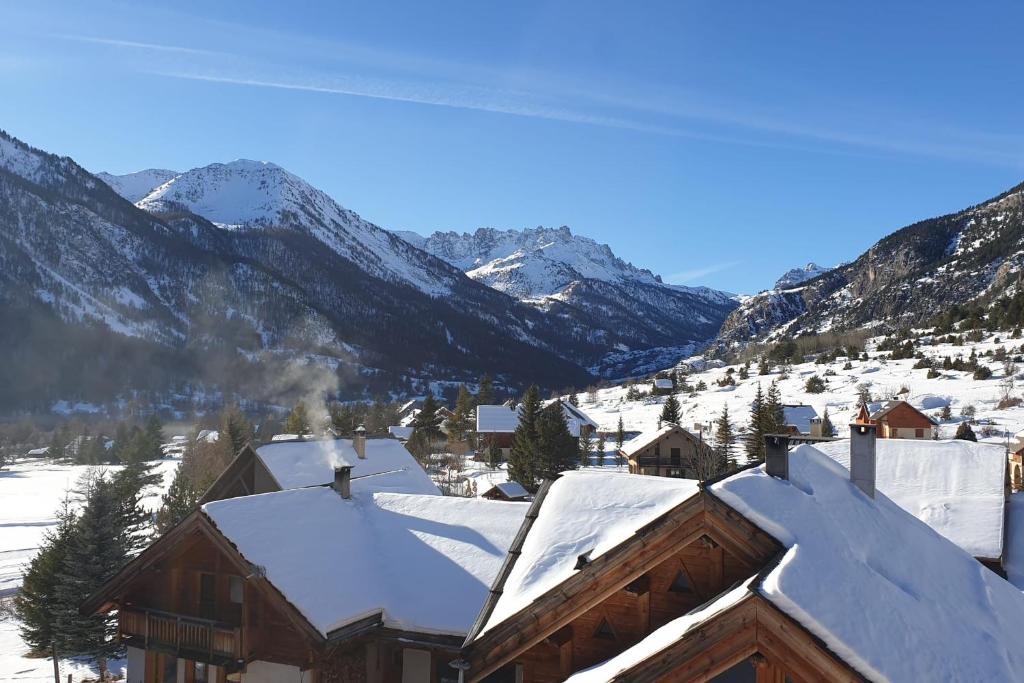 eine Ski-Lodge mit schneebedeckten Dächern und Bergen in der Unterkunft Apartment Croix Carail - Completely renovated in Roubion in Névache