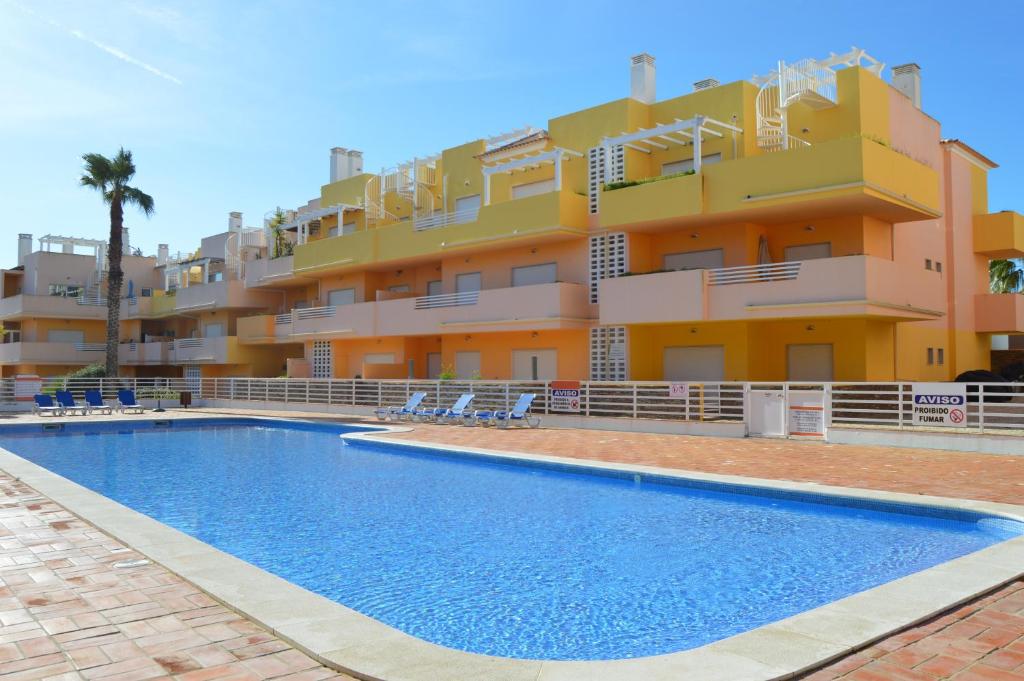 a building with a swimming pool in front of a building at Apartamentos Cabanas Golf in Tavira