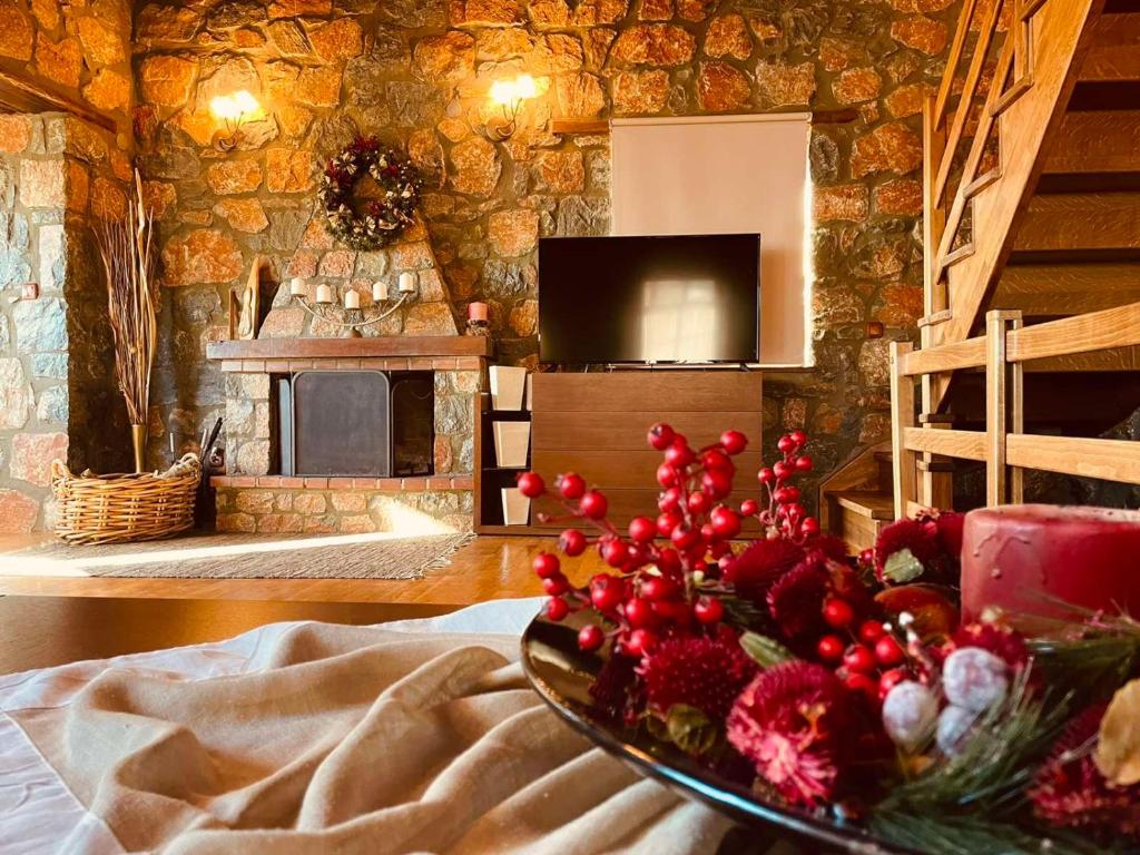 a living room with a stone wall with a table with flowers at Chalet D'elite in Palaios Agios Athanasios