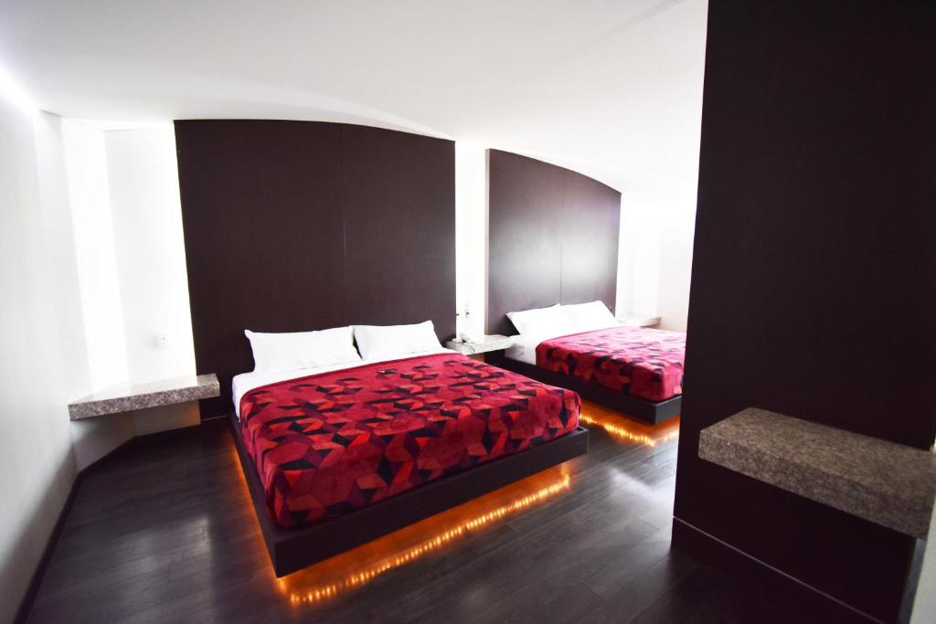 1 dormitorio con 2 camas con colchas rojas y ventana en Hotel Via La Villa, en Ciudad de México