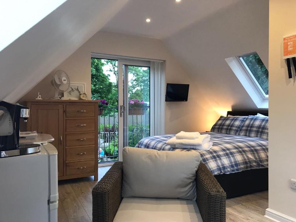 a bedroom with a bed with a chair and a window at The Firs - Englefied studio in Douglas