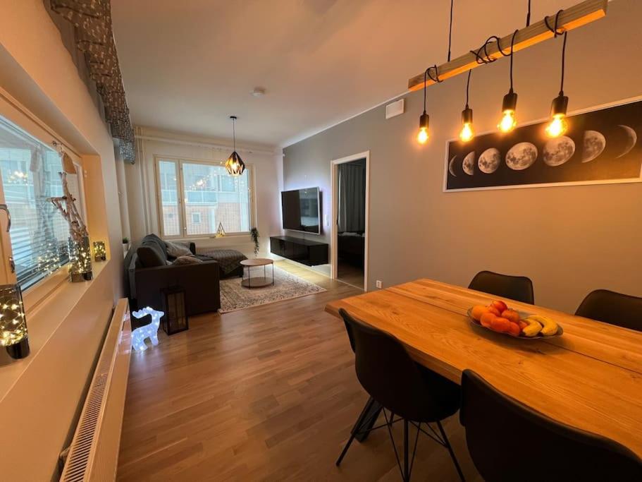 uma cozinha e sala de estar com uma mesa de madeira e cadeiras em Suite - King Size Bed - Gym&Wifi - Indoor Parking em Rovaniemi