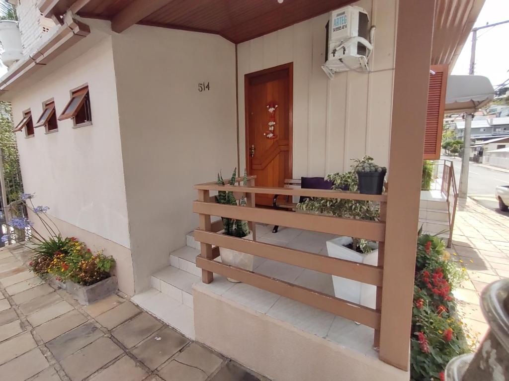 une maison avec une porte en bois et quelques plantes dans les escaliers dans l'établissement Hospedagem Don Panizzi, à Bento Gonçalves
