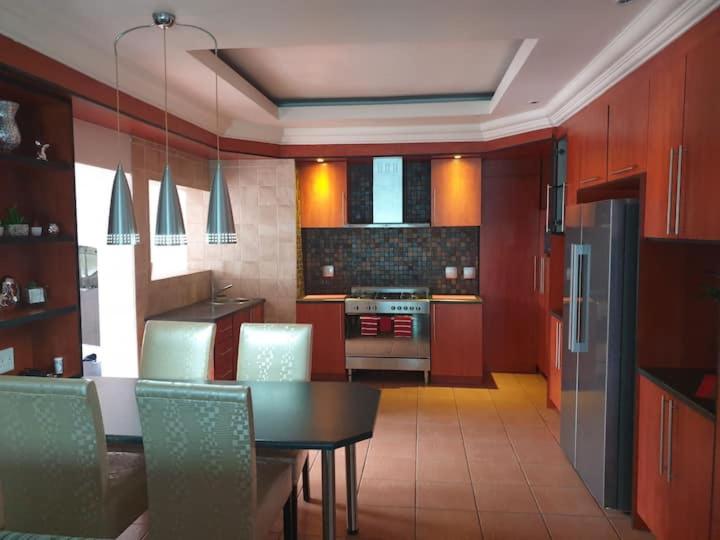a kitchen with a table and a kitchen with red cabinets at Genie's Nest 5 in Pretoria