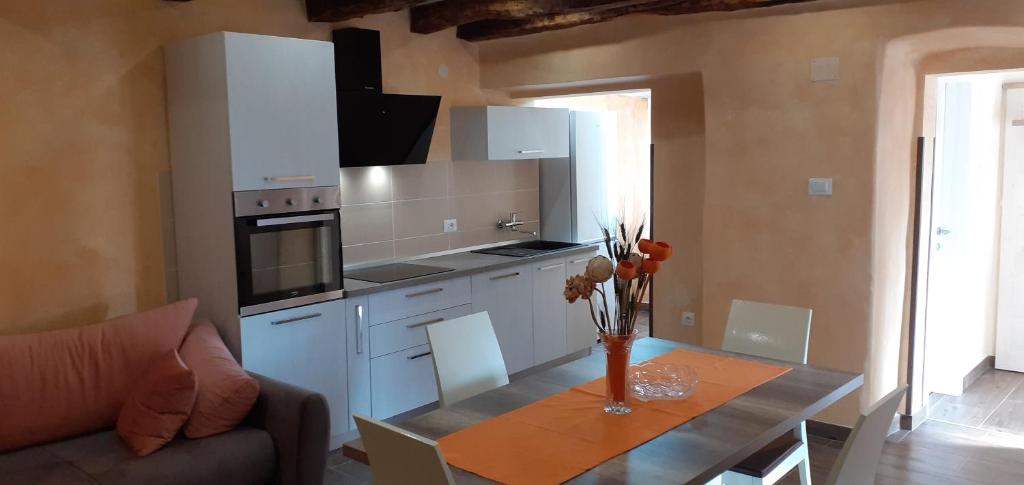 a kitchen with white cabinets and a table and a couch at Apartman Miljenka in Pazin