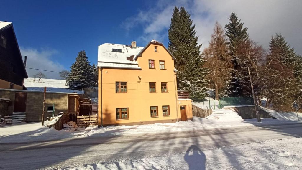 una gran casa amarilla en la nieve en Vila Kokrhačka, en Loucná pod Klínovcem