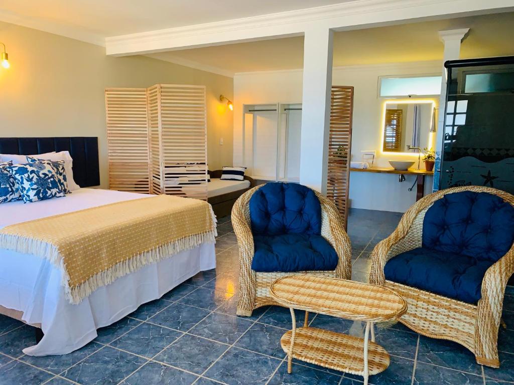 - une chambre avec un lit et deux chaises dans l'établissement Suíte frente mar e pés na areia, à Japaratinga