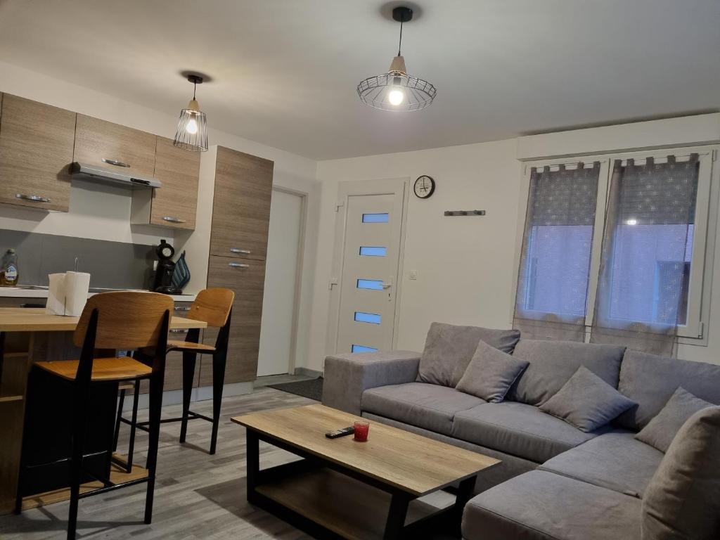ein Wohnzimmer mit einem Sofa und einem Tisch in der Unterkunft Agréable maisonnette à proximité du centre-ville in Oyonnax